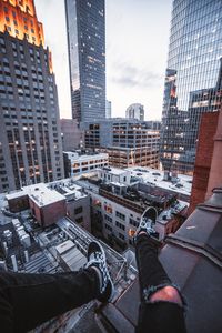 Low section of man and buildings in city against sky