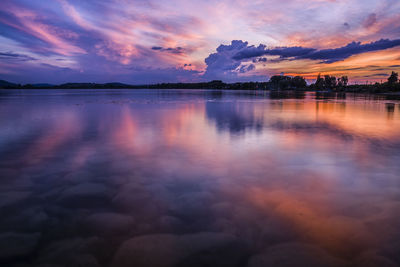 Scenic view of lake against dramatic sky during sunset