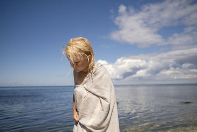 Blond girl wrapped in towel on beach