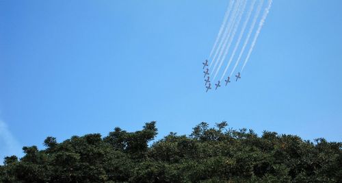 Low angle view of airplanes flying against clear blue sky