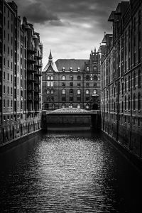 Canal amidst buildings in city against sky