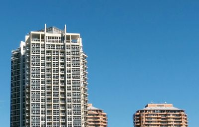 Low angle view of modern buildings against clear blue sky