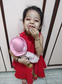 Portrait of cute girl holding red at home