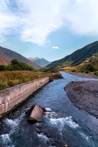 Scenic view of river amidst mountains against sky