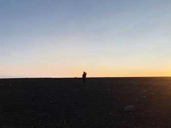Silhouette man standing on beach against clear sky