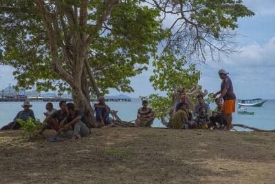 Group of people sitting on land against trees