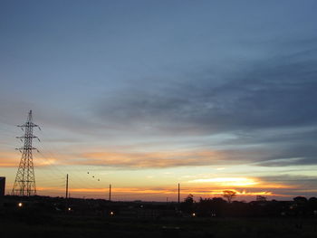 Silhouette of communications tower against dramatic sky during sunset