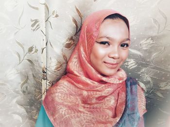 Portrait of smiling teenage girl against floral fabric