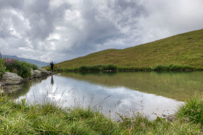 View of calm lake against cloudy sky