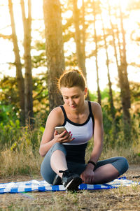 Full length of young woman sitting on land