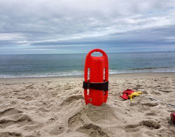 Red container on beach against sky