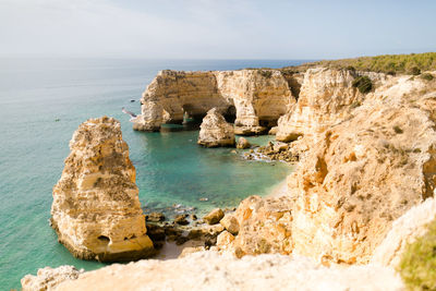 Scenic view of rocks on shore against sky