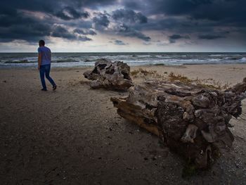 Man standing on beach against sky during sunset