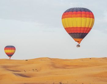 Hot air balloon flying in desert against sky