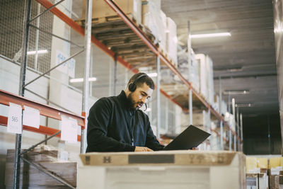Male manual worker reading document at logistics warehouse
