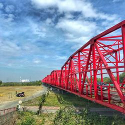 Red train on railroad track against sky