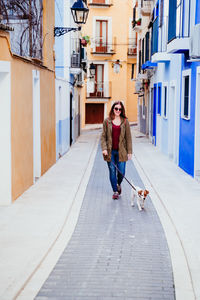 Full length of woman with dog in city