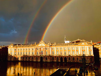 Panoramic view of rainbow over river against cloudy sky
