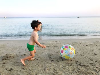 Boy playing on beach against sea