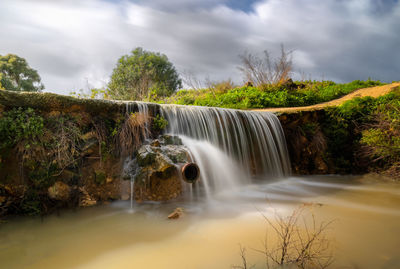 Scenic view of waterfall against sky