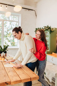 Young man and woman romantic couple couple hug at the kitchen while coocking and backing