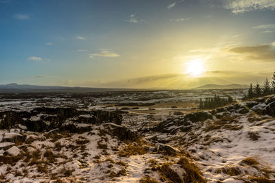 Scenic view of snow covered land against sky during sunset