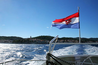 Flag on sea against clear blue sky