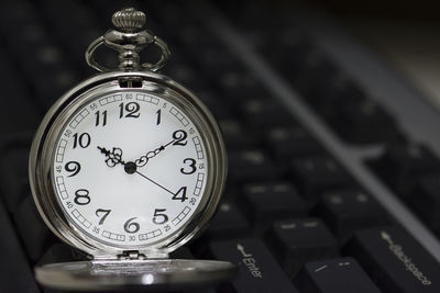 Close-up of pocket watch on computer keyboard