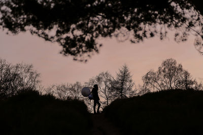 Silhouette people on field against sky during sunset