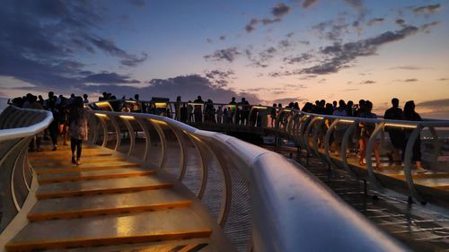 Group of people at observation point against sky during sunset