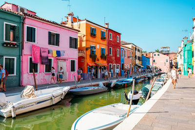 Boats moored in canal by buildings against clear sky