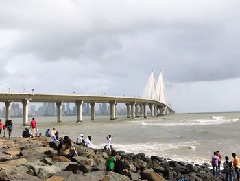 Group of people on bridge over sea against sky