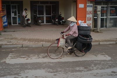 Man riding bicycle on street against buildings in city