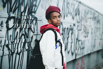 Portrait of boy standing against graffiti wall