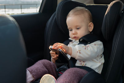 Portrait of cute boy using phone while sitting in car
