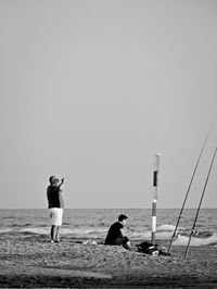 People on beach against clear sky