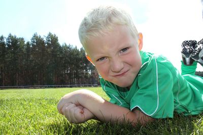 Portrait of boy lying down on field