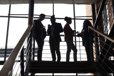 Multiracial male and female entrepreneurs discussing with each other on staircase in corporate event