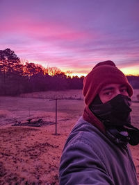 Portrait of man wearing hat on field against sky during sunset