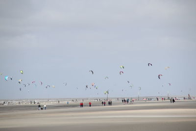 Parachutes at sandy beach against sky