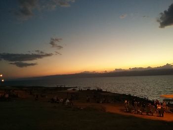 Silhouette people on beach against sky during sunset