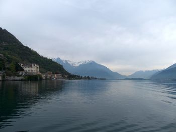 Scenic view of lake by mountains against cloudy sky