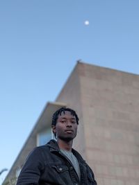 Portrait of young man standing against clear sky