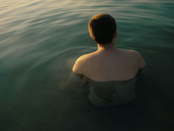 Rear view of shirtless man in water