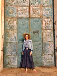 Portrait of smiling woman standing against closed door 