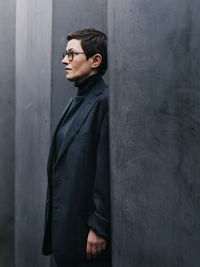 Portrait of young woman standing against wall