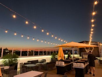 Chairs and tables at restaurant against sky at night