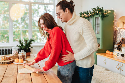 Young man and woman romantic couple couple hug at the kitchen while coocking and backing