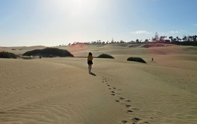 Rear view of man walking on desert