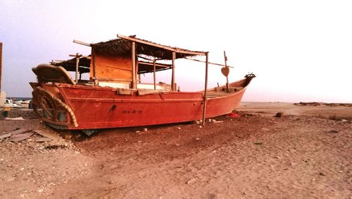 Boat moored on beach against clear sky